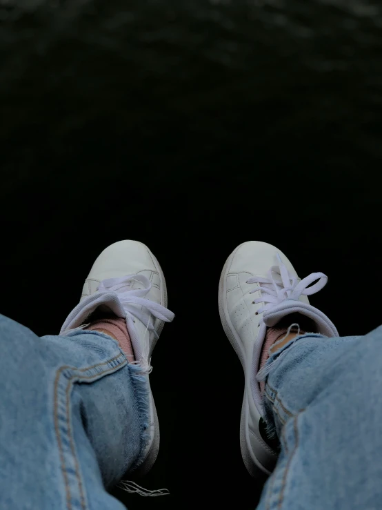 someone is sitting on their feet with white sneakers on