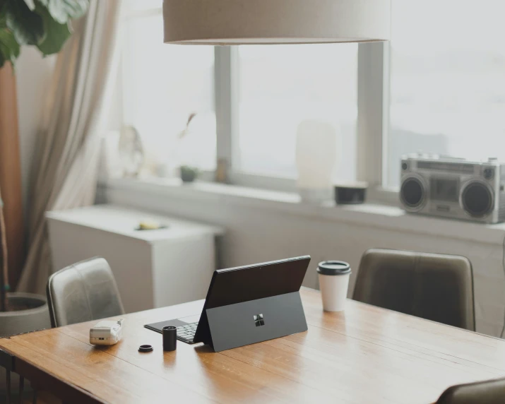 laptop sitting on a table beside a table lamp and speakers