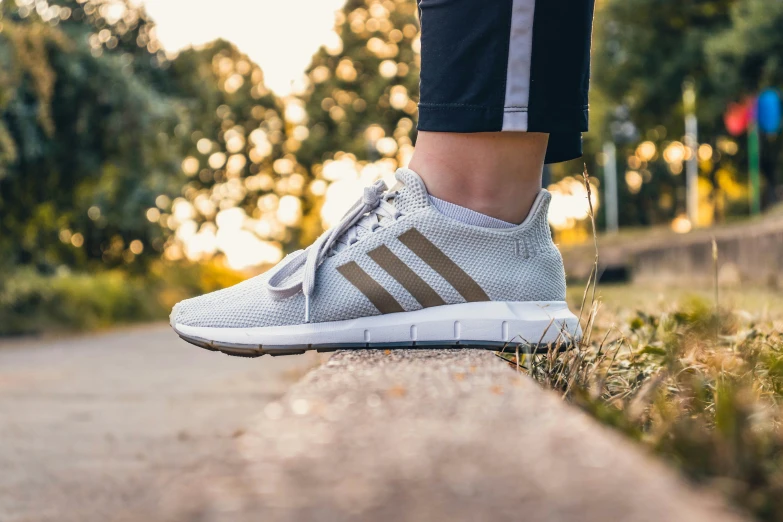 a person is walking down a street wearing white shoes