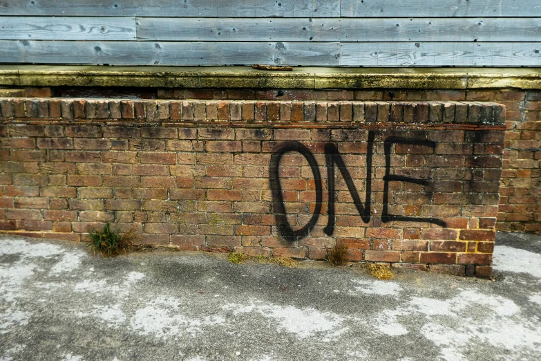 the word one written in black spray paint on a brick wall