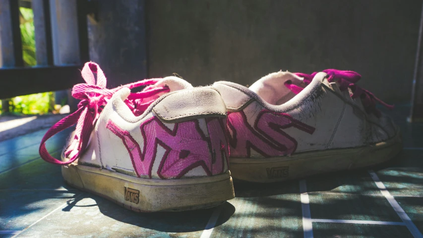 a tennis shoe with a pink ribbon on the toe