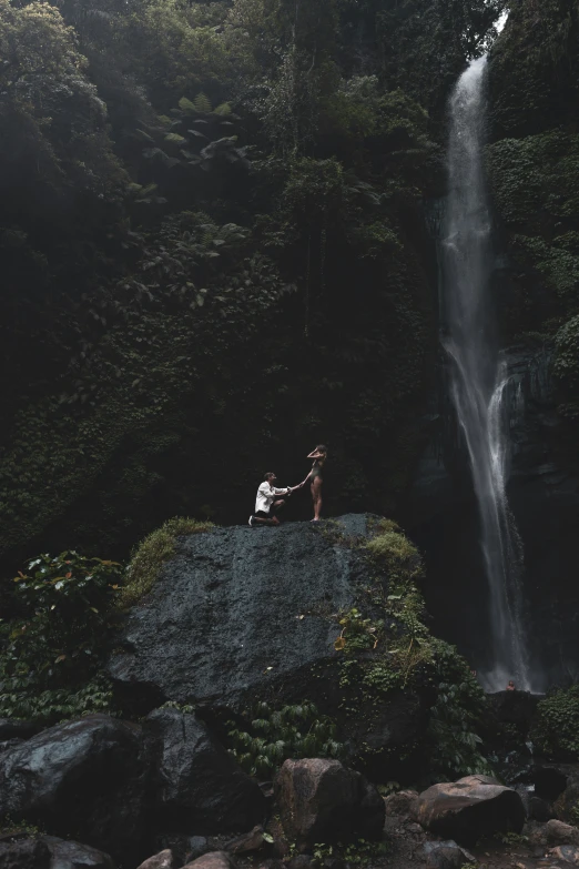 a couple standing near a waterfall with one man next to it