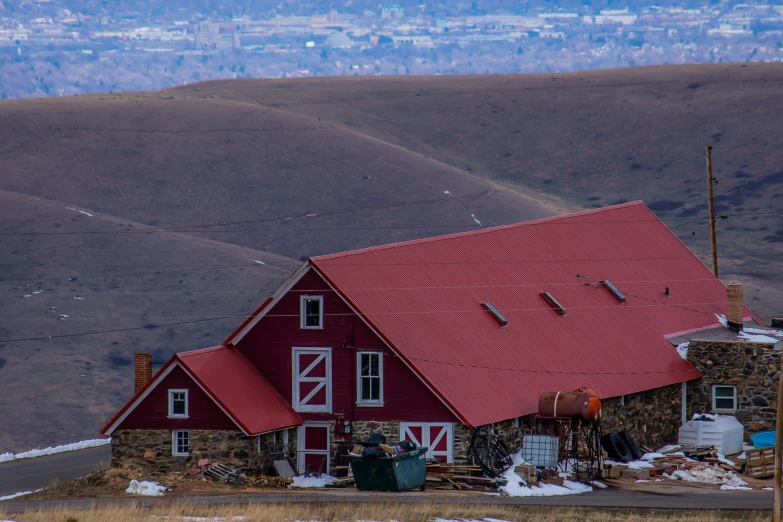 red barn on top of a mountain with a sky background