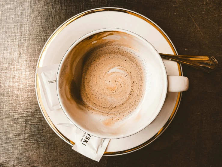 a cup with white foam on it is sitting next to a wooden spoon