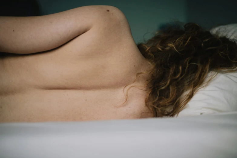 an image of a person laying on a bed with her back turned