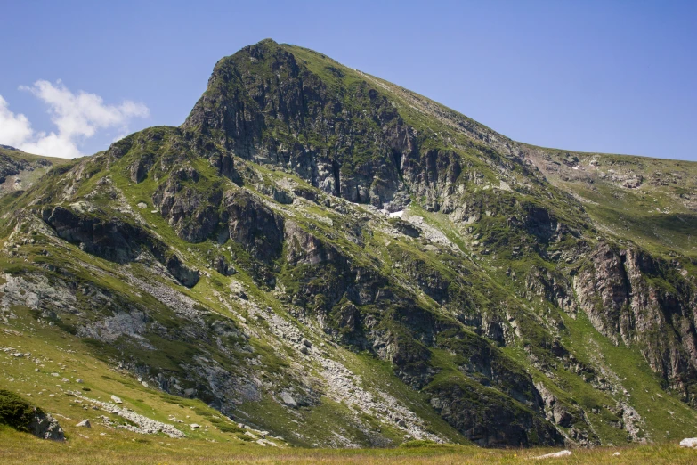 mountains rise on top of a grassy hill