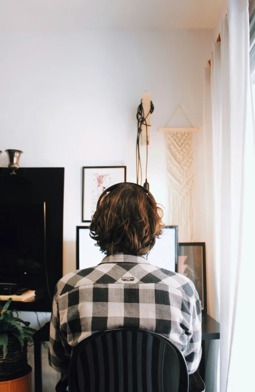 person with messy hair sitting at desk in front of computer