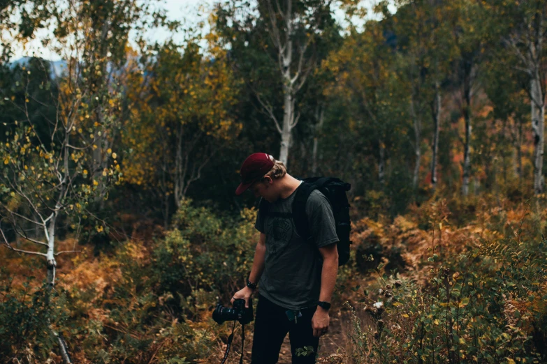 a man walking down a dirt trail carrying skis