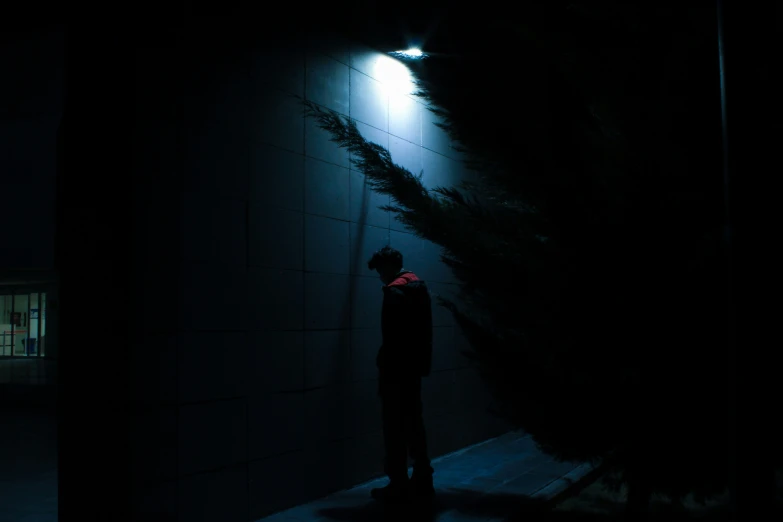 the silhouette of a man in black is illuminated by a street lamp