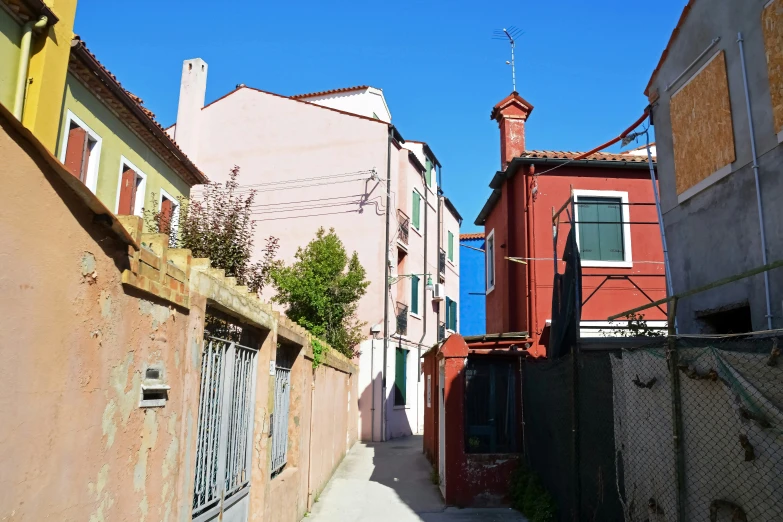 a small alley with a tall clock tower and a fence in front