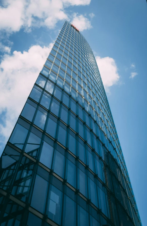 a tall glass building with blue sky and clouds