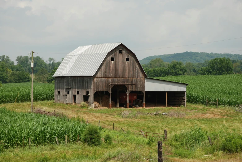 a large barn sits out in the middle of a grassy field