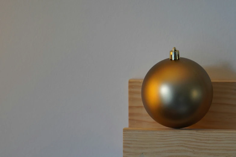 a ball shaped gold sculpture on top of a wooden base