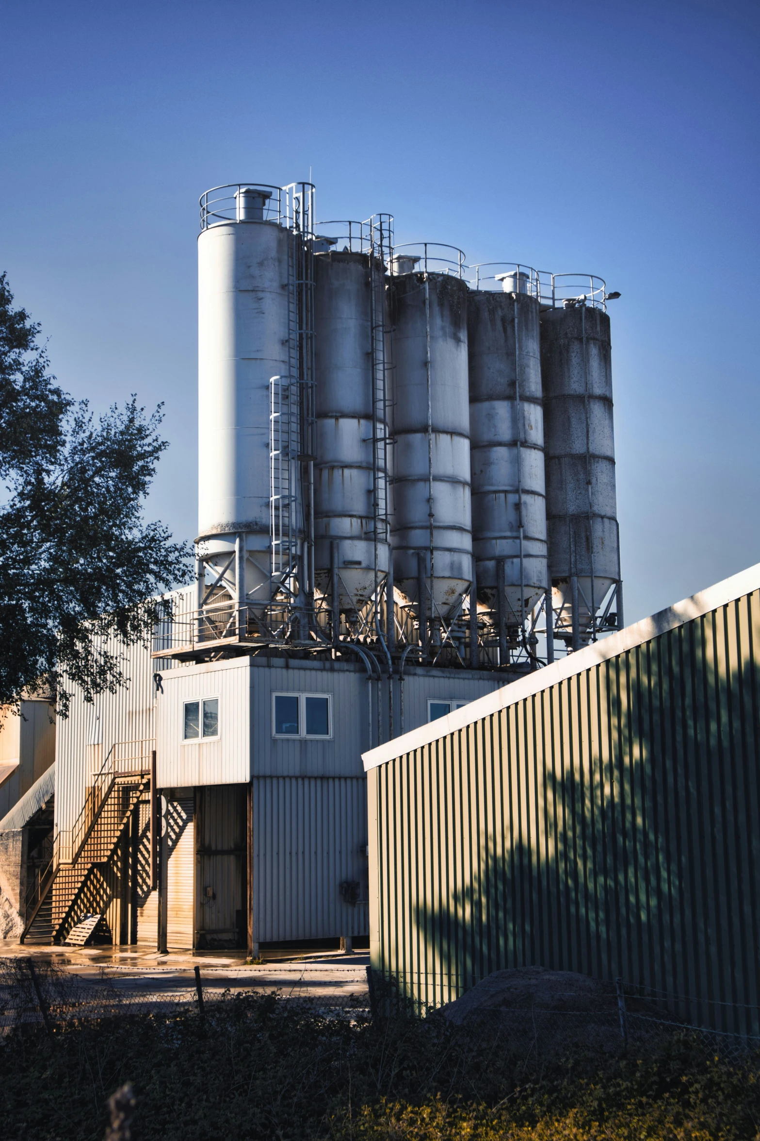 several large, shiny storage tanks sit against a wall