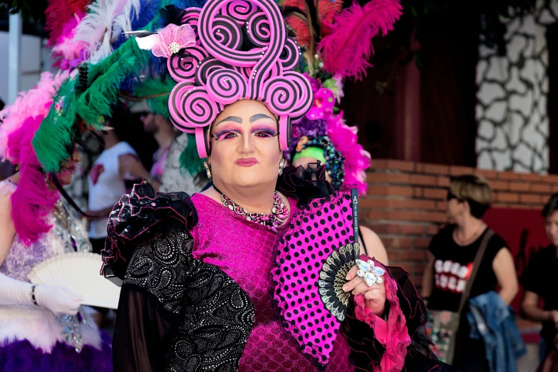 a woman in bright colored clothing holding a pink, green and purple scarf