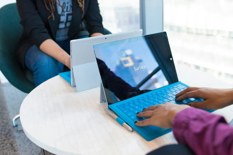 two women are on a laptop in the middle of a conference room