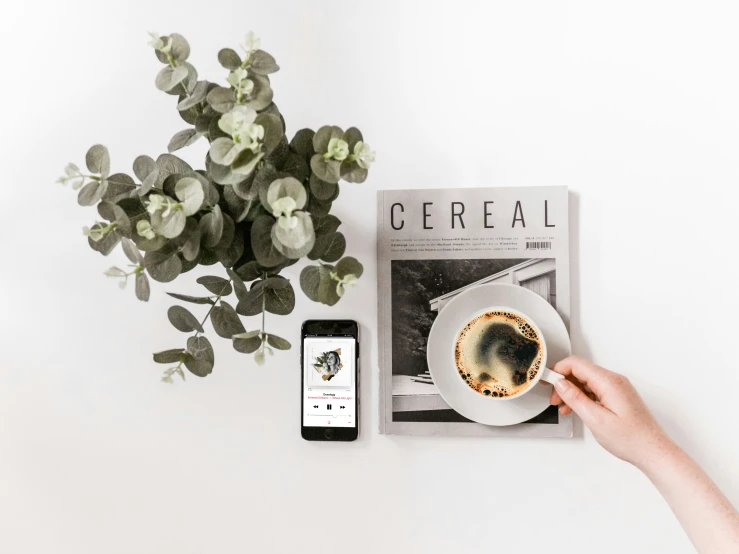 a person holding a cup of coffee while looking at a cell phone