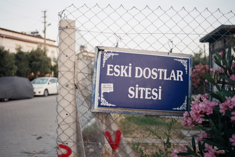 a sign posted on a fence by a bunch of flowers