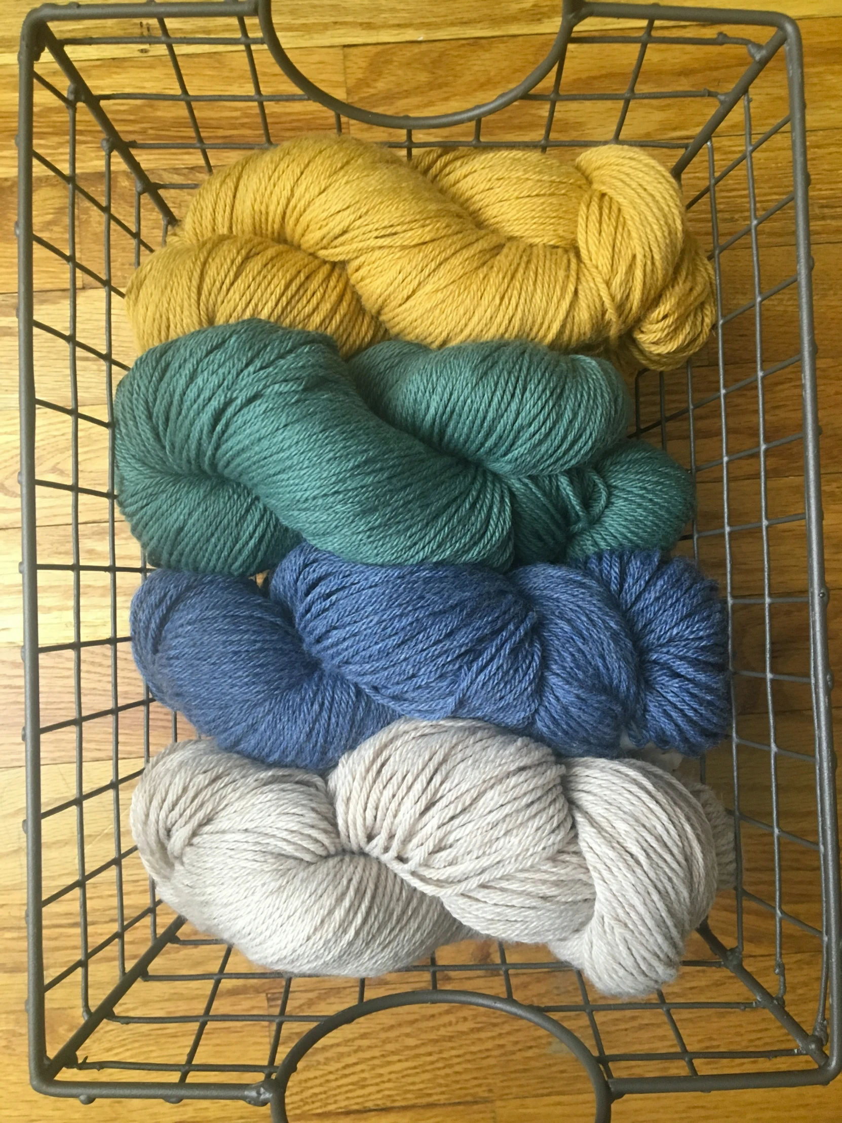 the skeins of yarn are sitting on the wire basket