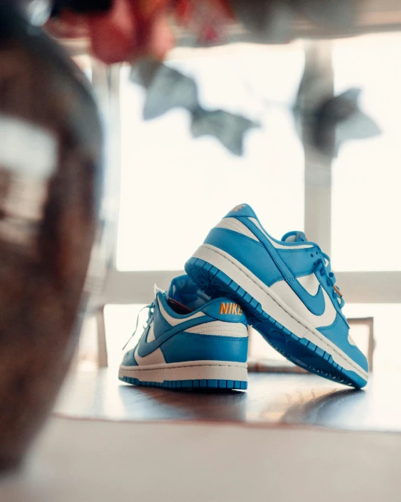 a pair of sneakers sit on a wooden table