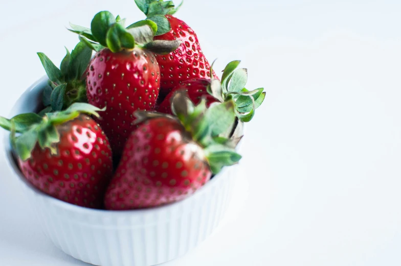 a bowl filled with strawberries sitting on top of a white counter