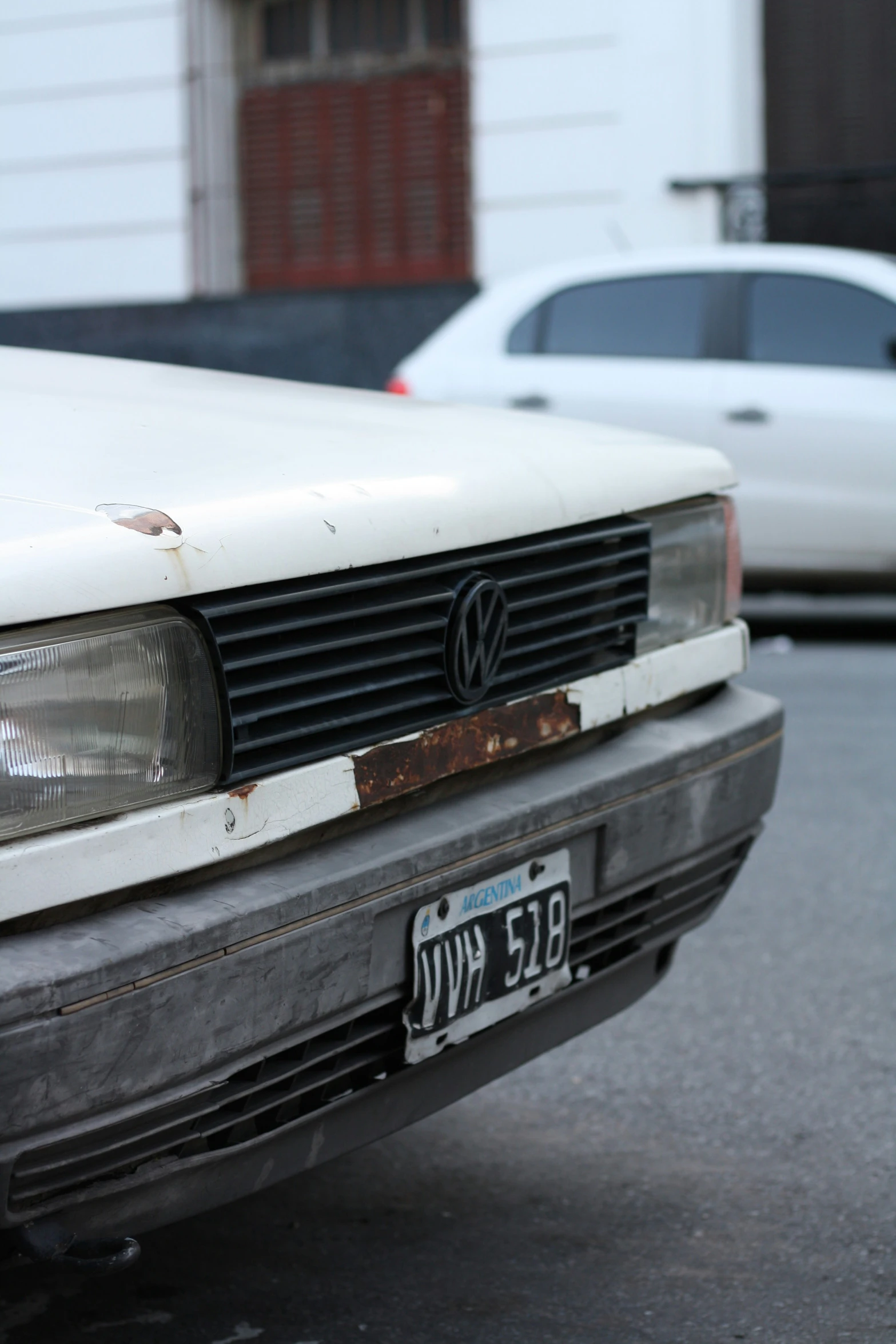 the front end of a white volkswagen car parked in a parking lot