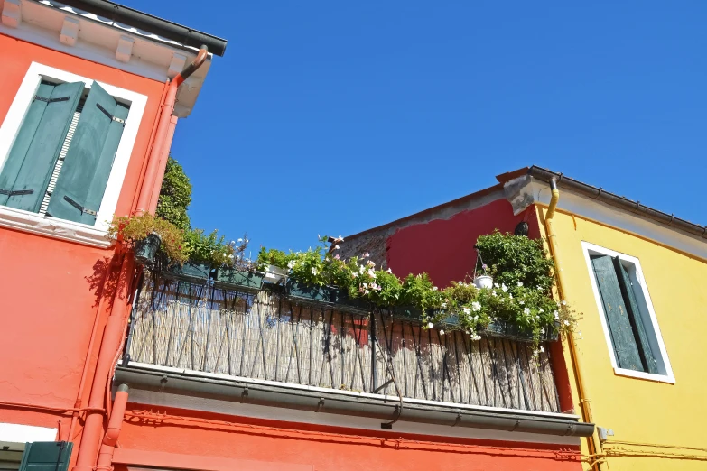 a red building next to two buildings with a balcony and green trees