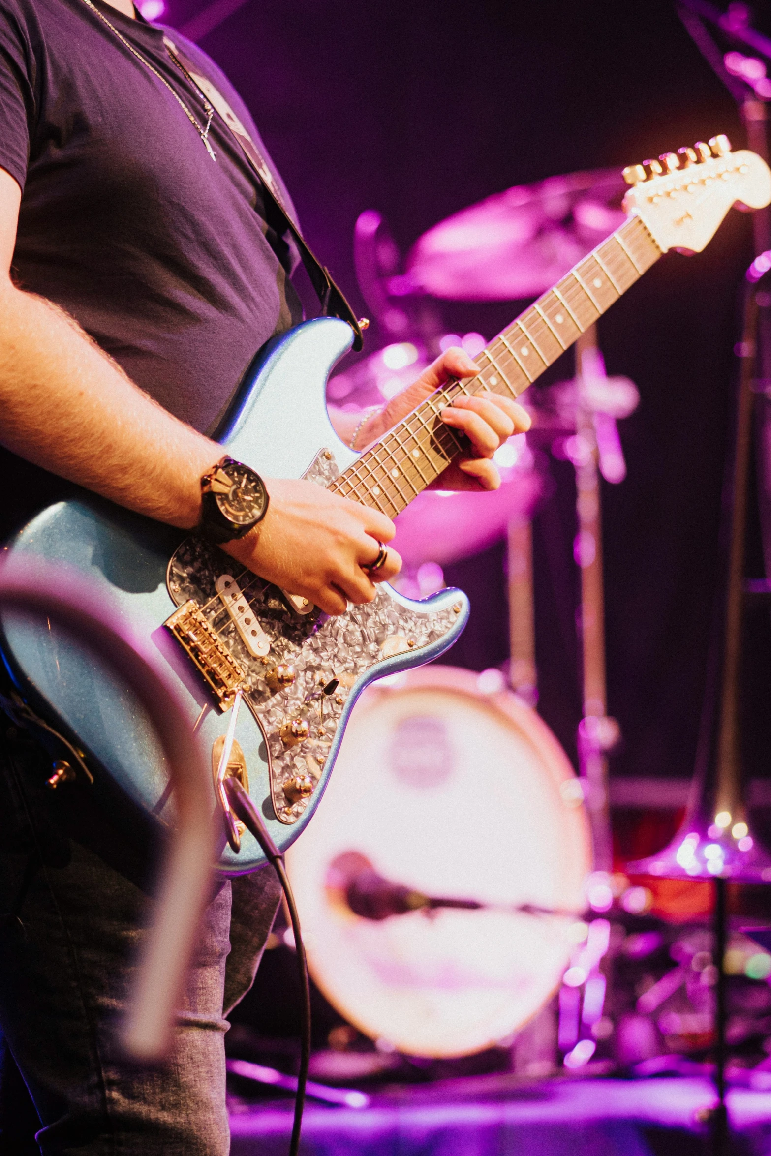 a man with a clock on his left arm plays guitar