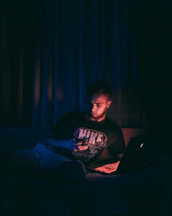 man sitting on bed and looking at laptop screen
