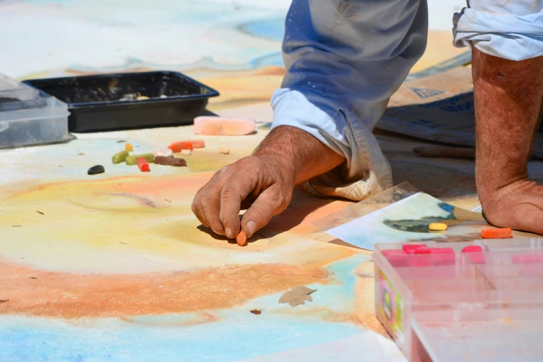 a man with his hands on the ground and colorful chalk