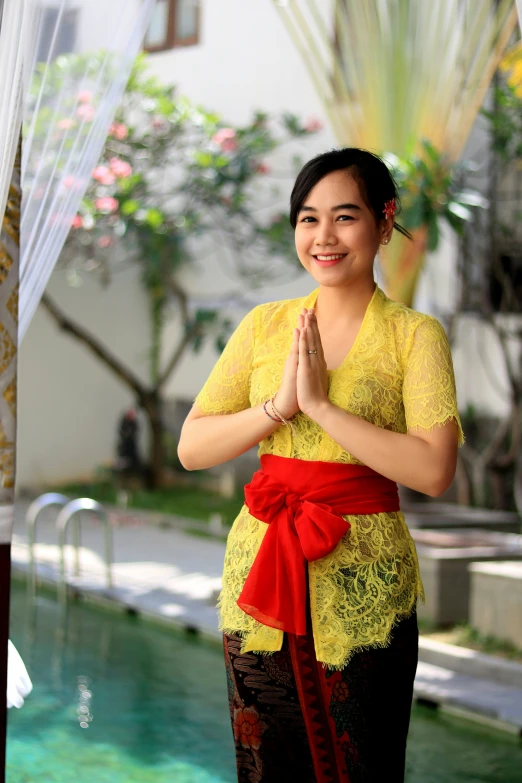 a woman is smiling while wearing a yellow top and red ribbon