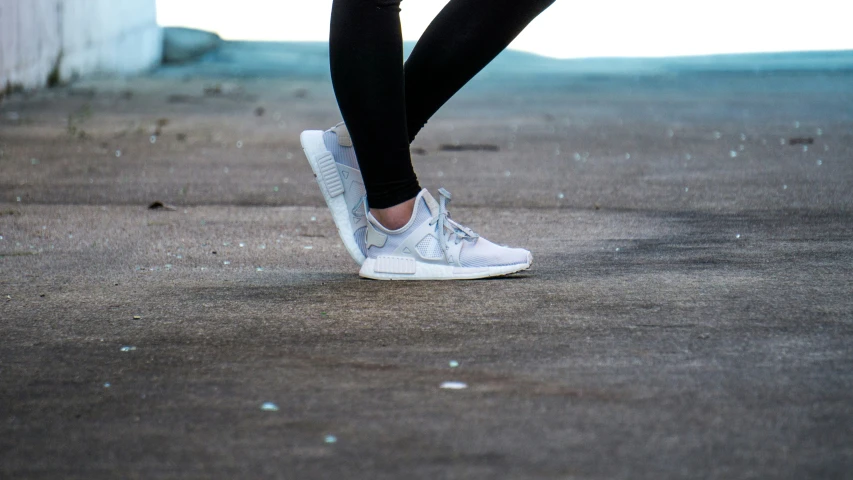close up po of person with white sneakers on cement