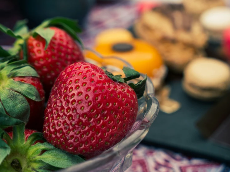 a glass bowl of strawberries next to other snacks