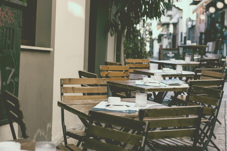 many wooden tables and chairs sitting on the sidewalk