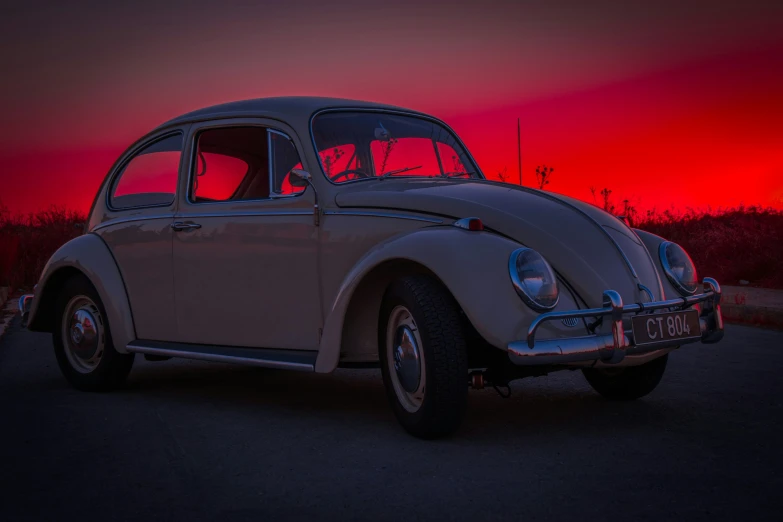 the beetle is parked on the road in front of the setting sun