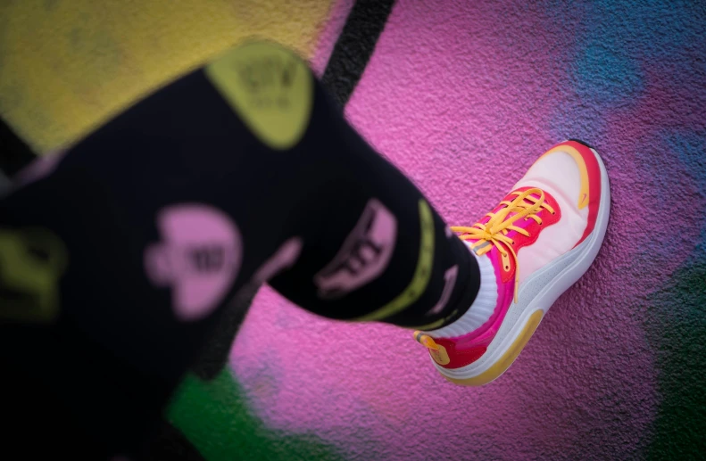 a person's colorful shoes as they stand on a wall