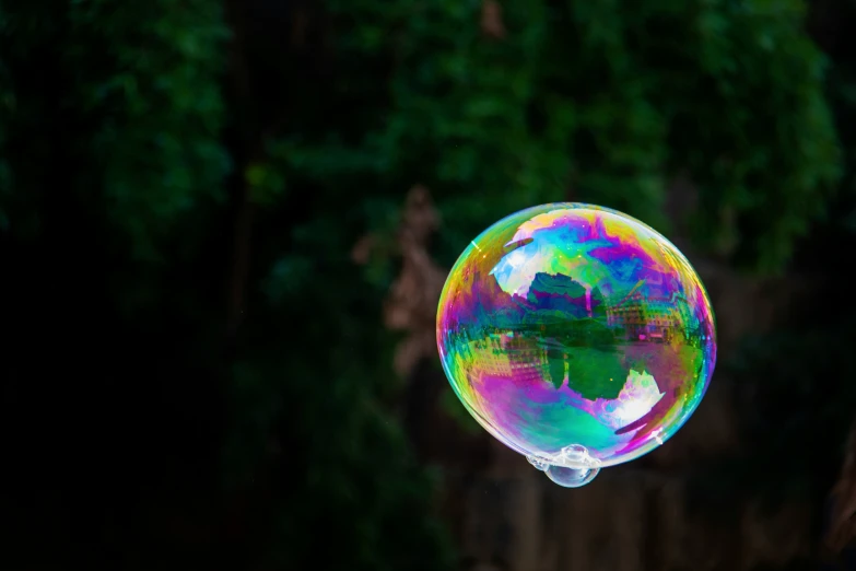 a bubble floating in the air next to a forest