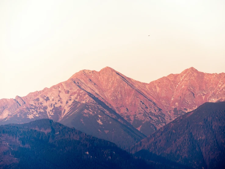 the silhouette of a mountain with some birds flying in it