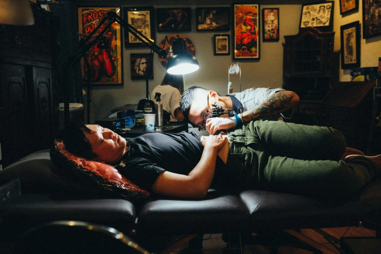 a man with a tattoo and his arm resting on a woman's neck