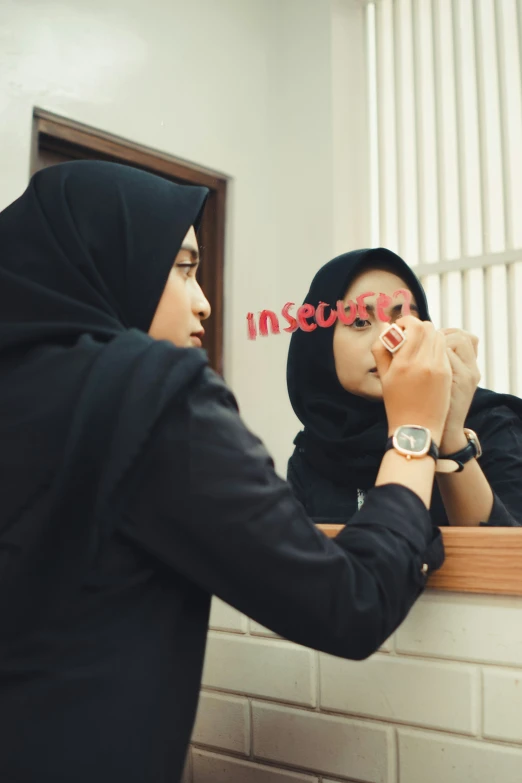 a woman writing on her forehead in front of a mirror