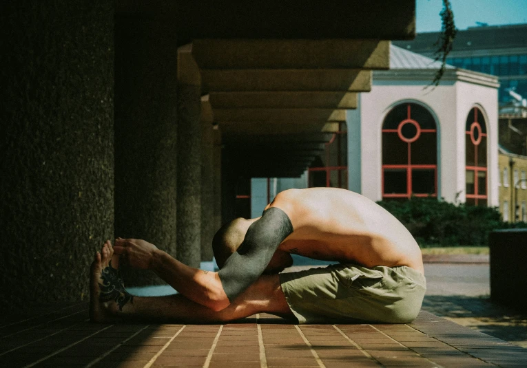 a person sitting on a sidewalk touching the ground