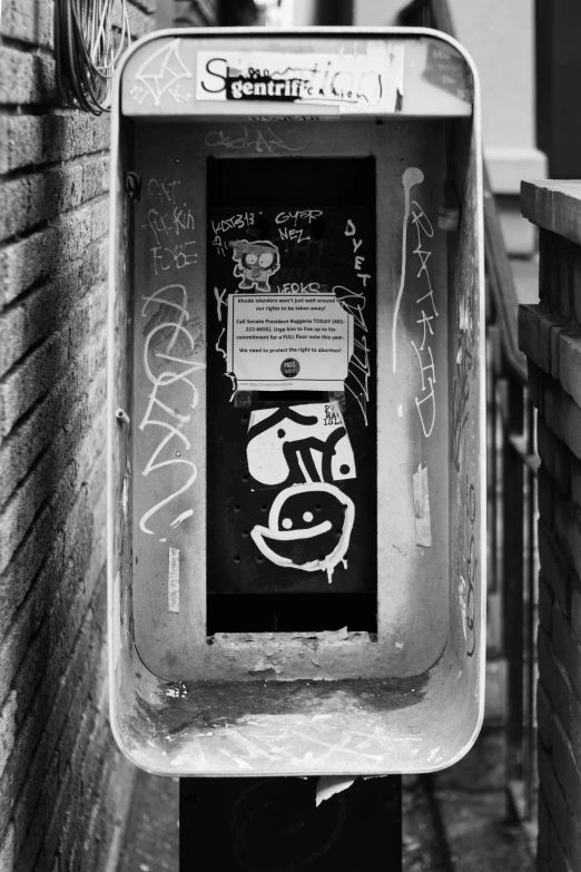 a public pay phone with graffiti writing on the side