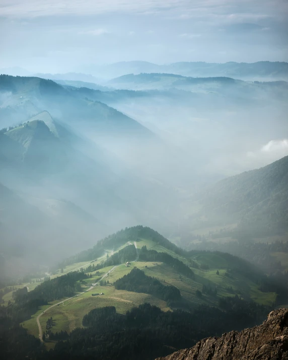 mountains are covered with green grass and mist as seen from the top