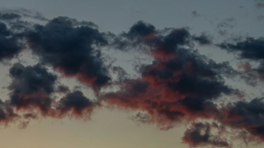 a plane is in the distance, with it's wing flying through the clouds