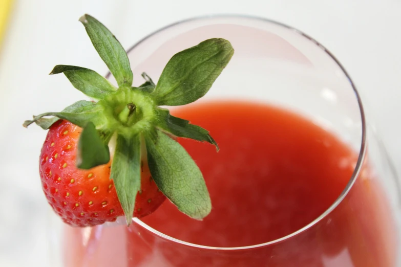 a red liquid is garnished with a green leaf