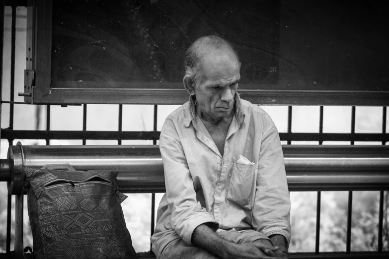 man sitting on bench with luggage and bag in the background