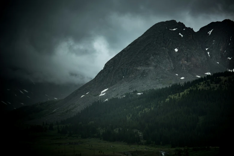 two tall mountains surrounded by dark clouds and trees