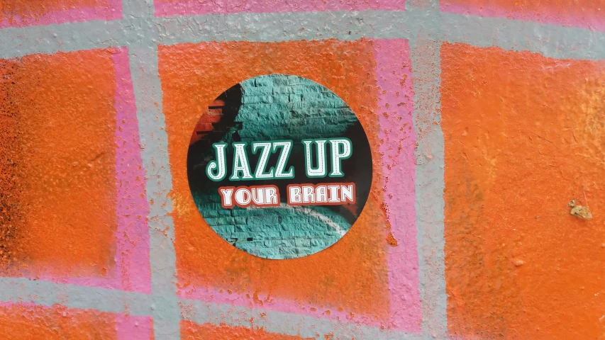 a round sticker on a brick wall saying, jazz up tom un