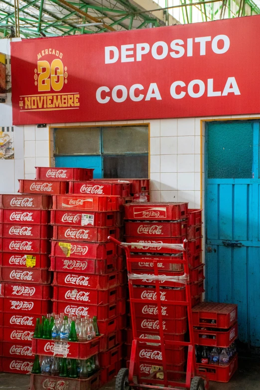 a pile of coca - cola crates sitting in front of a store