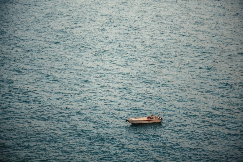 a lone small boat floating in the middle of a body of water